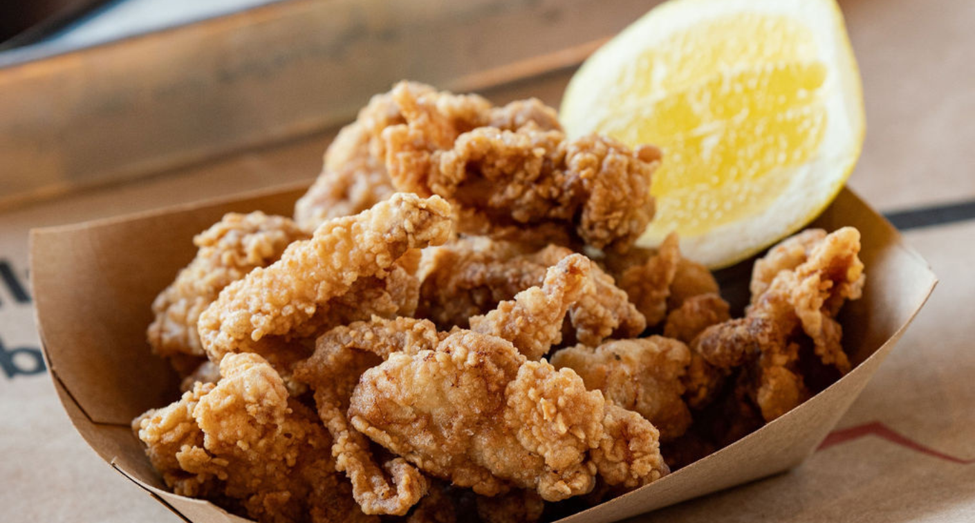 Image of fried chicken oysters and a lemon in a boat.