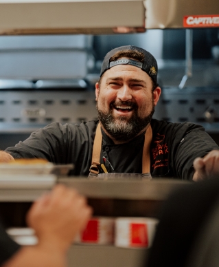 Image of man smiling behind the counter in the kitchen at Crack Shack